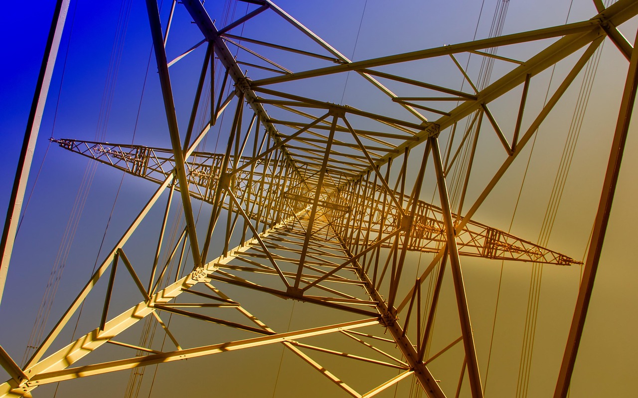 A steel transmission tower carrying power lines across an open landscape.